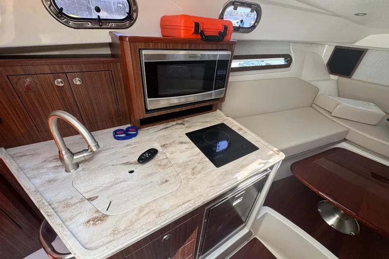  Yacht Photos Pics 2020 Pursuit OS 325 Offshore interior with kitchenette, microwave, and seating area.