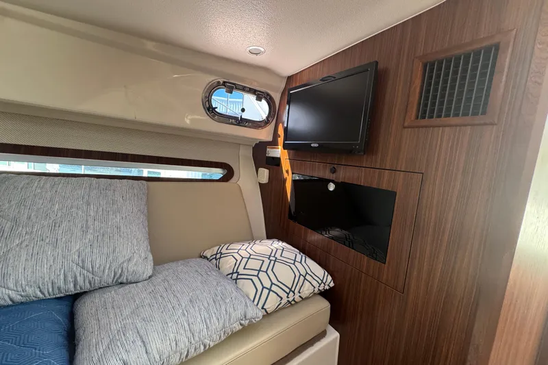  Yacht Photos Pics 2020 Pursuit OS 325 Offshore cabin interior with TV, cushions, and wood paneling.