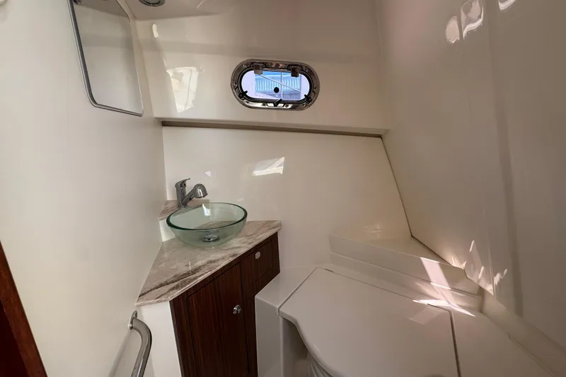  Yacht Photos Pics 2020 Pursuit OS 325 Offshore boat bathroom with glass sink and porthole window.