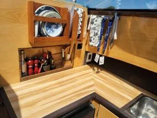  Yacht Photos Pics Compact kitchen area in a 2010 Mission-Craft Mis 35 boat, featuring wooden cabinetry and utensils.