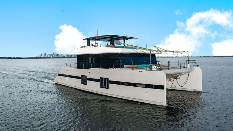 Island Majesty Yacht Photos Pics Luxurious 2018 Sunreef 70 yacht cruising on open water with city skyline backdrop.