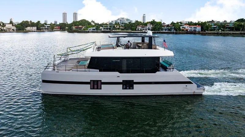 Island Majesty Yacht Photos Pics 2018 Sunreef 70 yacht cruising on a scenic waterway with city skyline backdrop.