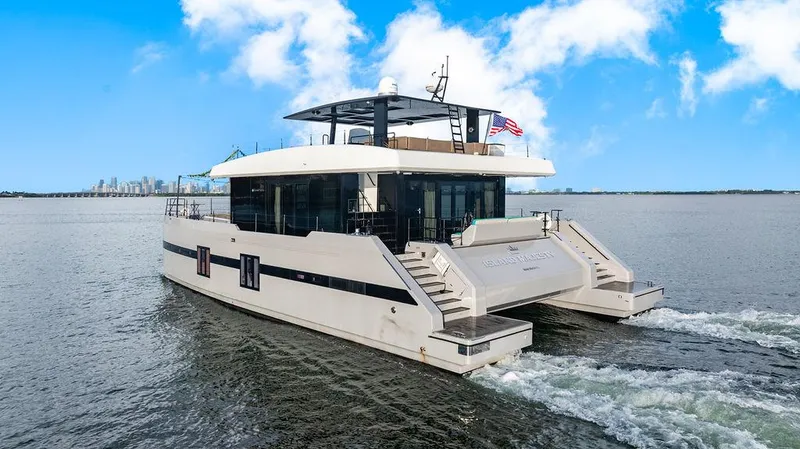 Island Majesty Yacht Photos Pics Luxurious 2018 Sunreef 70 yacht cruising on open water with city skyline backdrop.