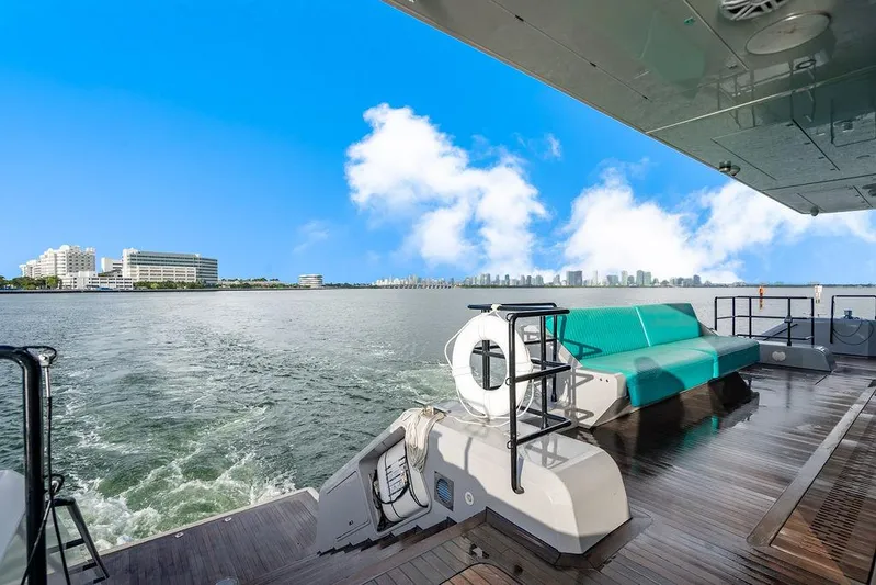 Island Majesty Yacht Photos Pics Luxurious Sunreef 70 yacht deck with turquoise seating, overlooking a vibrant city skyline.