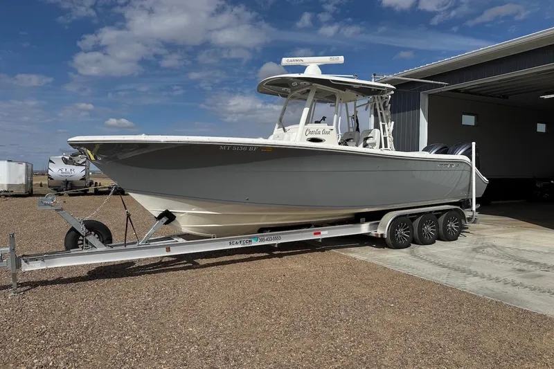  Yacht Photos Pics 2023 Cobia 301 Center Console boat on trailer, parked outside a garage.