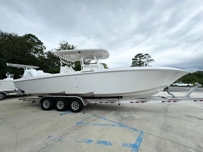  Yacht Photos Pics 2025 Fountain 34TE boat on trailer, parked outdoors, cloudy sky background.