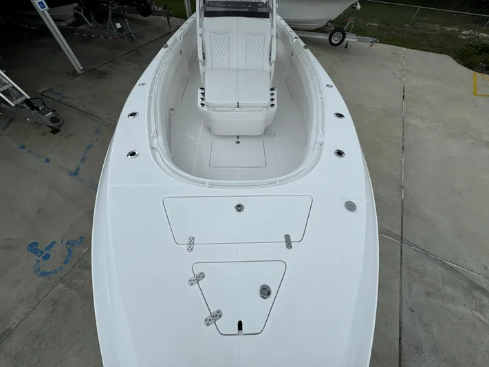  Yacht Photos Pics 2025 Fountain 34TE boat, white deck, spacious seating, docked on concrete surface.