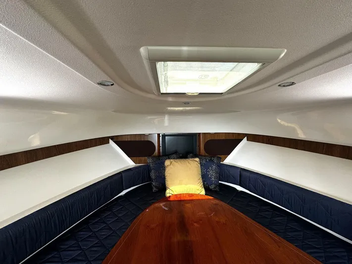 Liberty Yacht Photos Pics Interior cabin of a 2010 Pursuit OS 345 Offshore boat with wood table and cushions.