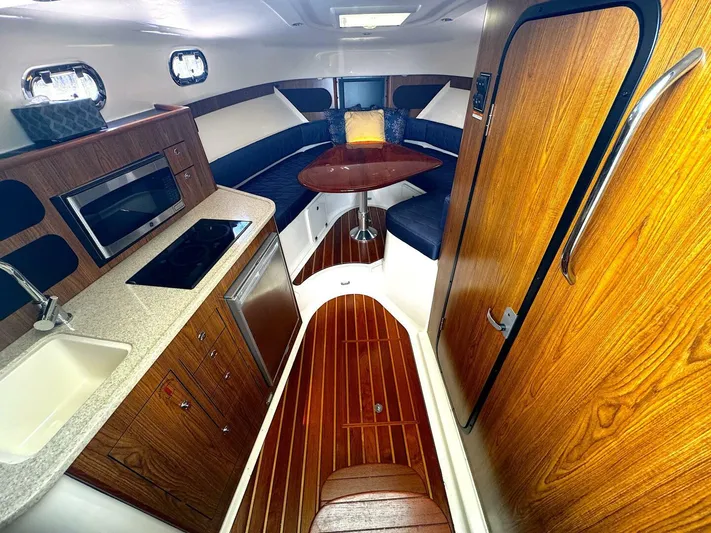 Liberty Yacht Photos Pics 2010 Pursuit OS 345 Offshore cabin with kitchenette, dining area, and wood finishes.