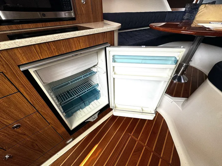 Liberty Yacht Photos Pics 2010 Pursuit OS 345 Offshore boat interior with open refrigerator and wooden cabinetry.