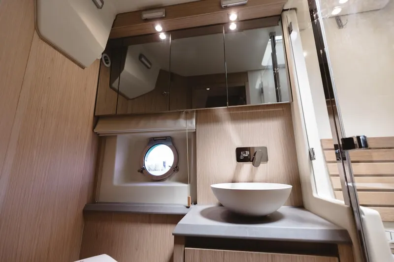  Yacht Photos Pics Luxurious bathroom in 2015 Beneteau Monte Carlo 5 yacht with modern fixtures and porthole window.