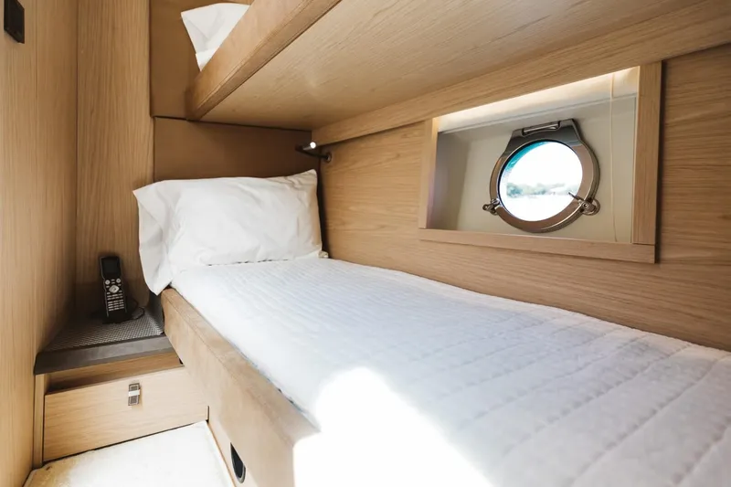  Yacht Photos Pics Cozy cabin interior of 2015 Beneteau Monte Carlo 5 yacht with porthole and single bed.