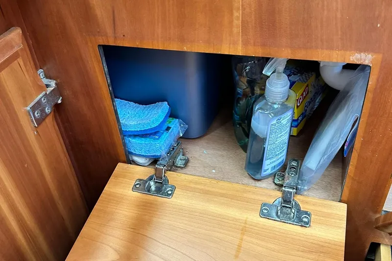 Champagne Lady Yacht Photos Pics Wooden cabinet with cleaning supplies, sponges, and soap, in a 2007 Sabre 386.