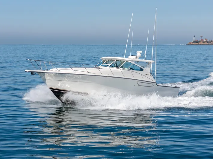 Magic Yacht Photos Pics 1992 Tiara Yachts 4300 Open cruising on the ocean near a lighthouse.