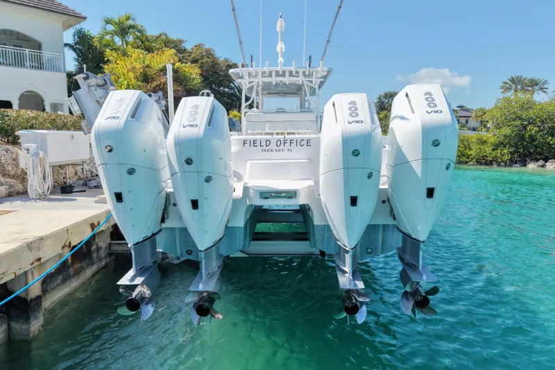  Yacht Photos Pics 2023 Invincible 46 Catamaran with four powerful outboard engines docked in clear water.