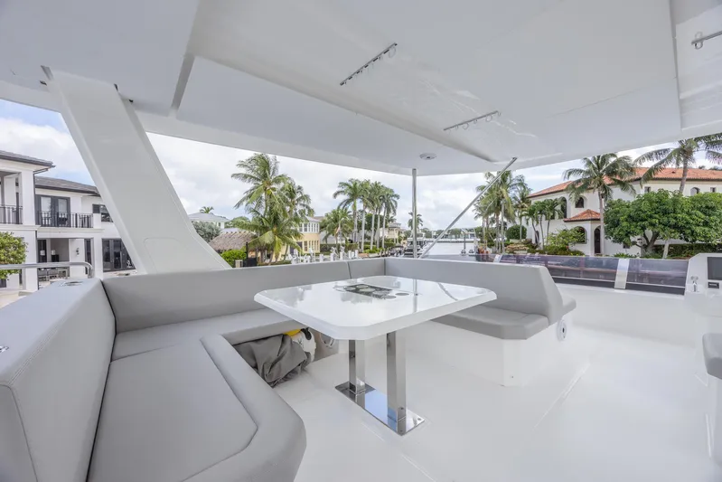  Yacht Photos Pics 2024 Leopard 53 Powercat yacht with spacious outdoor seating and table, surrounded by palm trees.