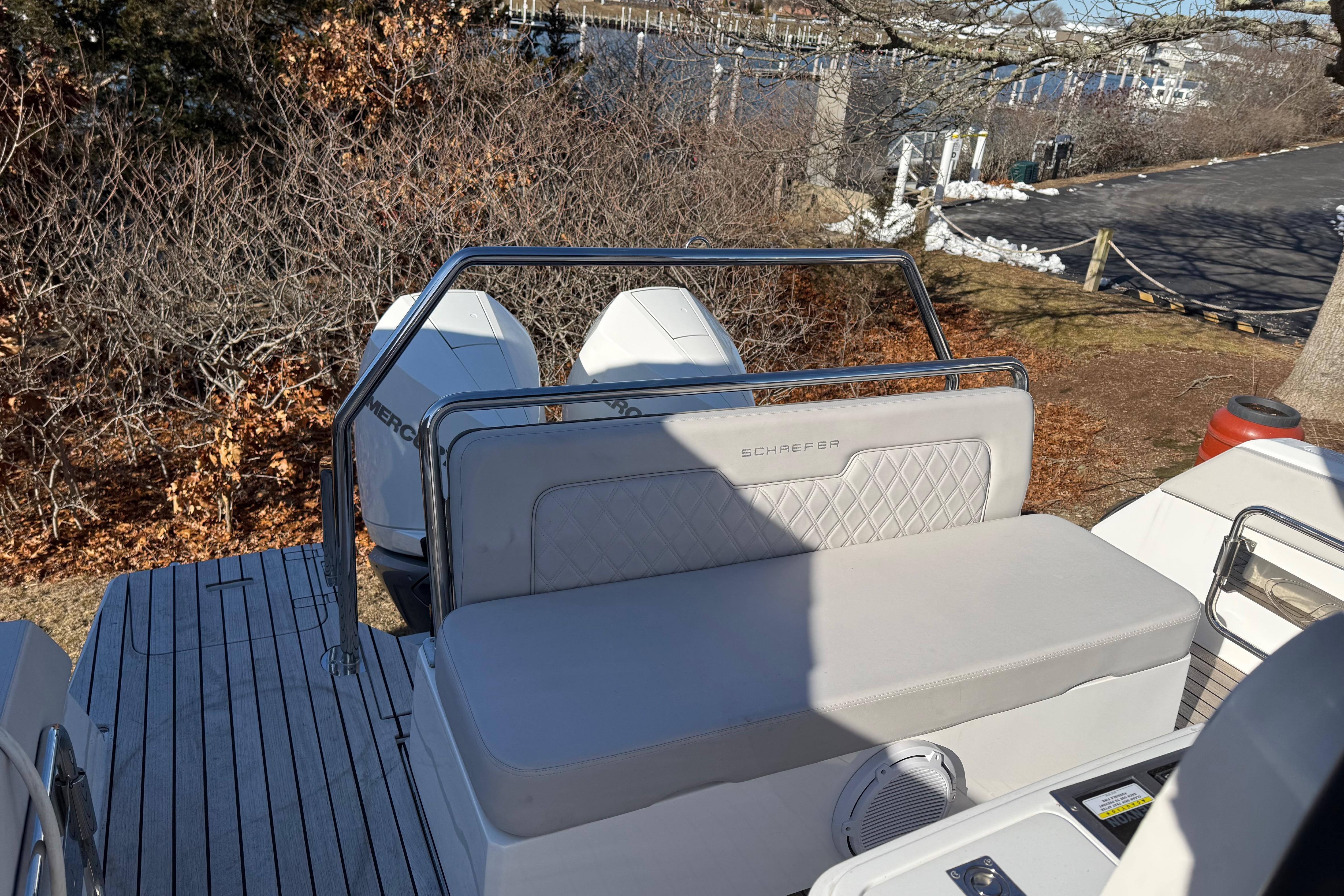 2024 Schaefer V33 boat with dual engines, docked near a wooded area.