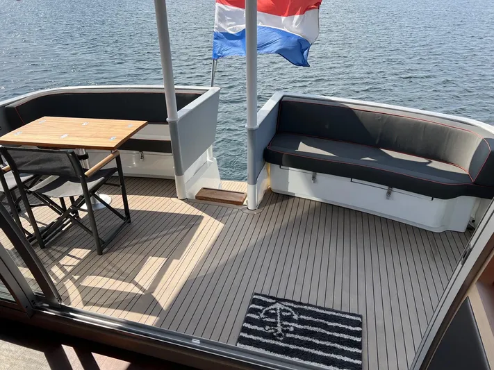  Yacht Photos Pics Deck of 2013 Vripack Utopia 58 yacht with seating, table, and flag.