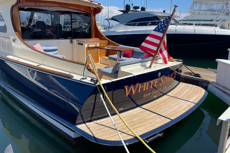 White Sauce Yacht Photos Pics 2017 Hinckley Talaria 43 Motoryacht docked, featuring elegant design and American flag.