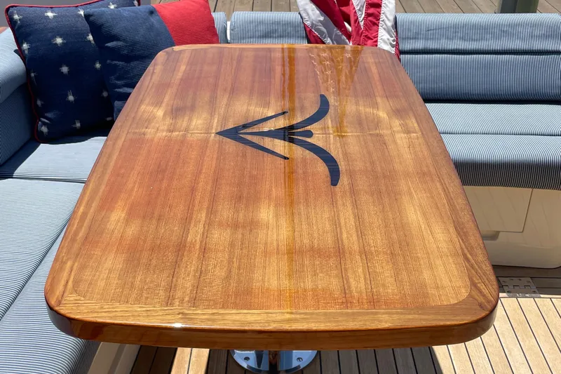 White Sauce Yacht Photos Pics Elegant wooden table on 2017 Hinckley Talaria 43 Motoryacht, surrounded by striped cushions.