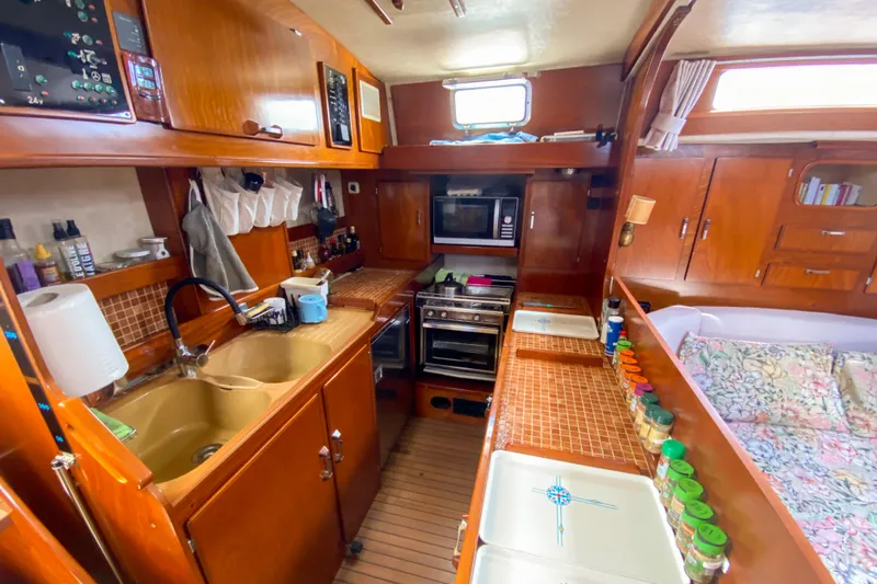  Yacht Photos Pics 1991 Amel Super Maramu yacht kitchen with wooden cabinetry, stove, and sink.