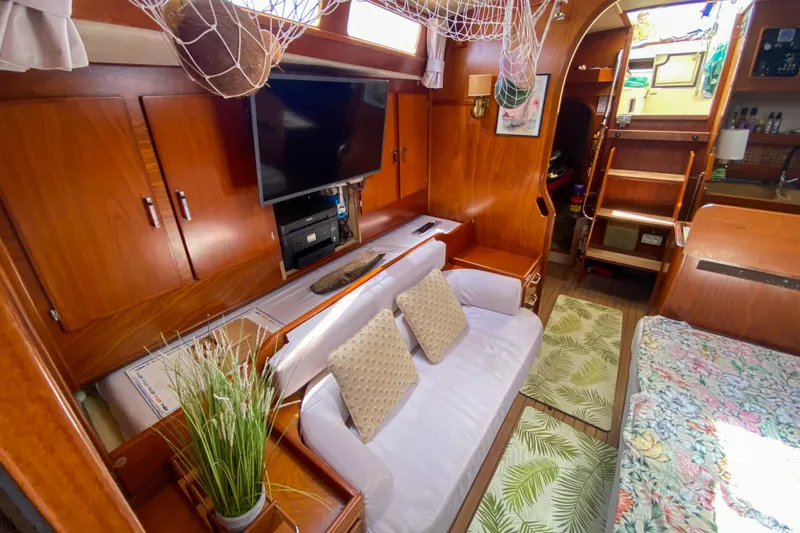  Yacht Photos Pics Interior of 1991 Amel Super Maramu yacht with cozy seating, TV, and wooden cabinetry.