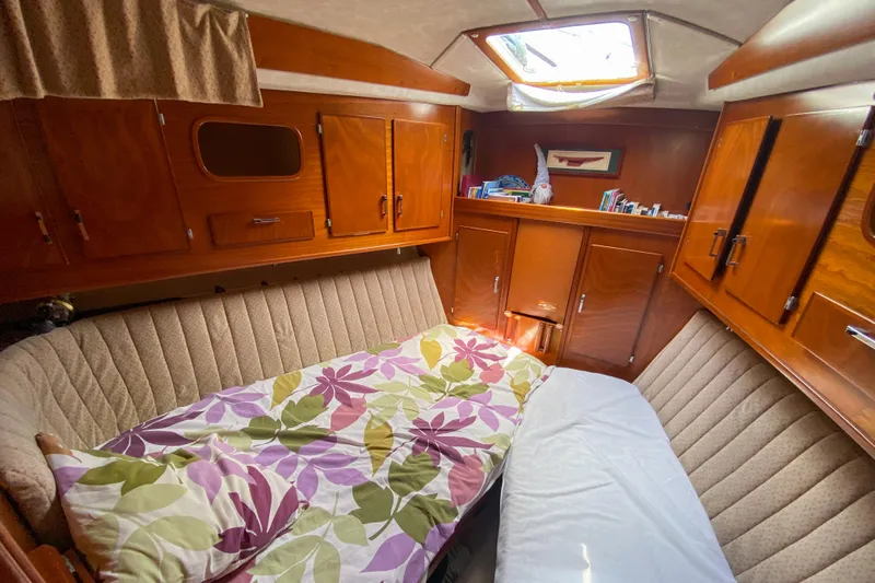  Yacht Photos Pics Cozy cabin interior of 1991 Amel Super Maramu sailboat with floral bedding and wooden cabinetry.