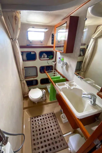  Yacht Photos Pics Bathroom interior of 1991 Amel Super Maramu yacht with sink, toilet, and storage shelves.