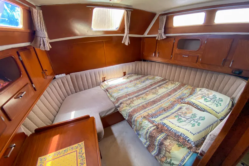  Yacht Photos Pics Cozy cabin interior of 1991 Amel Super Maramu sailboat with bed and wooden furnishings.