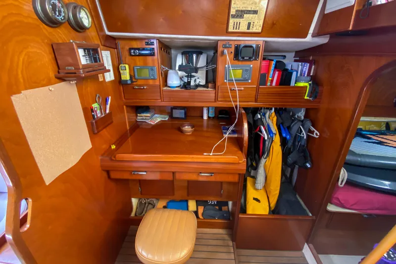  Yacht Photos Pics Navigation station inside a 1991 Amel Super Maramu yacht, featuring wooden cabinetry and nautical instruments.
