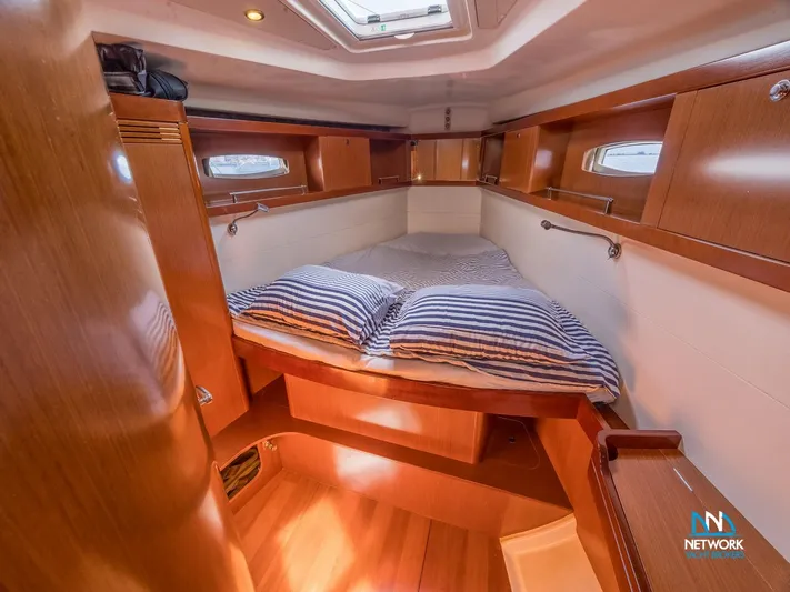  Yacht Photos Pics Cozy cabin interior of 2011 Beneteau Oceanis 46 sailboat with striped bedding.