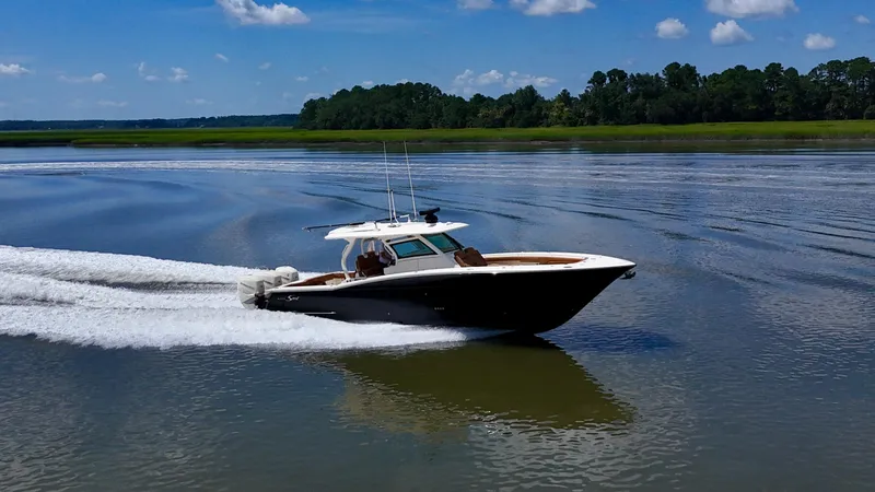 Wild Horses Yacht Photos Pics 2020 Scout 380 LXF boat cruising on a calm lake under a clear blue sky.
