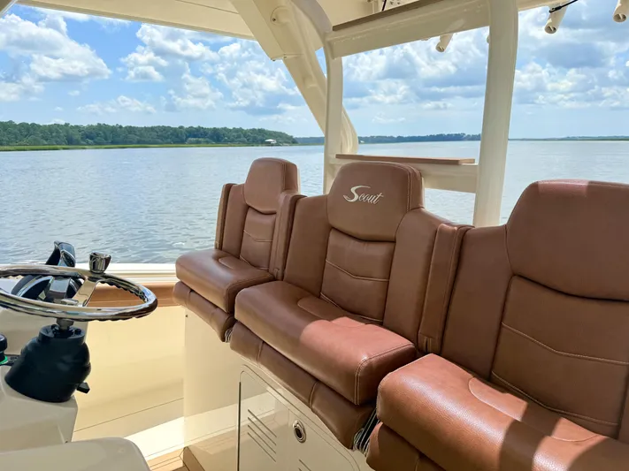 Wild Horses Yacht Photos Pics 2020 Scout 380 LXF boat interior with brown leather seats and steering wheel, overlooking serene water.