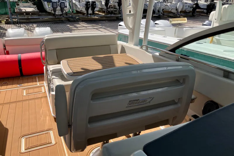  Yacht Photos Pics 2023 Boston Whaler 320 Vantage interior with seating and table, docked with other boats.