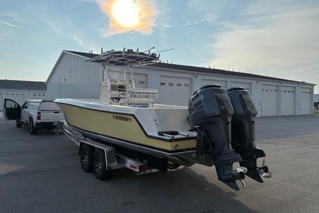 2003 Contender 27 Open boat with dual Yamaha engines on a trailer near a warehouse.