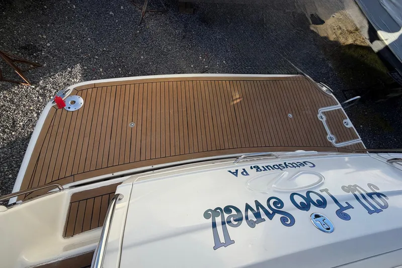 All Too Swell Yacht Photos Pics 2002 Regal Commodore 3860 boat with teak deck, docked on gravel.