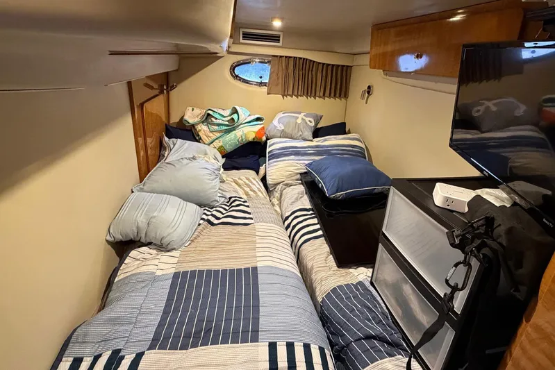 All Too Swell Yacht Photos Pics Cozy cabin interior of 2002 Regal Commodore 3860 with bed and TV.