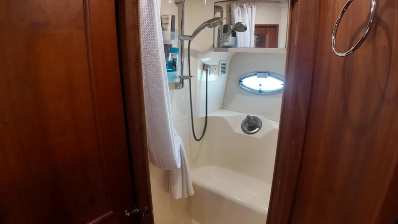 Yacht Photos Pics Shower area in 2002 Silverton 410 Sport Bridge yacht with wooden door and porthole window.
