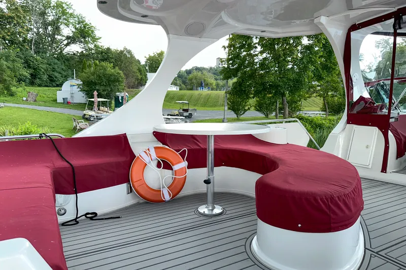  Yacht Photos Pics Luxury 2012 Bluewater 5200 yacht deck with red seating and table, surrounded by greenery.