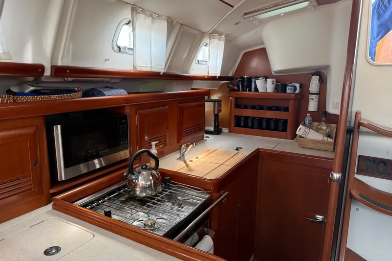 Aeolus Yacht Photos Pics Cozy kitchen in 2007 Beneteau 423 yacht with stove, microwave, and wooden cabinetry.