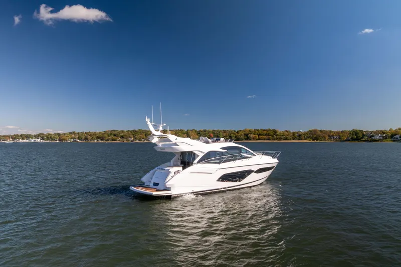 In The Moment Yacht Photos Pics 2018 Sunseeker Manhattan 52 yacht cruising on a serene lake under a clear blue sky.