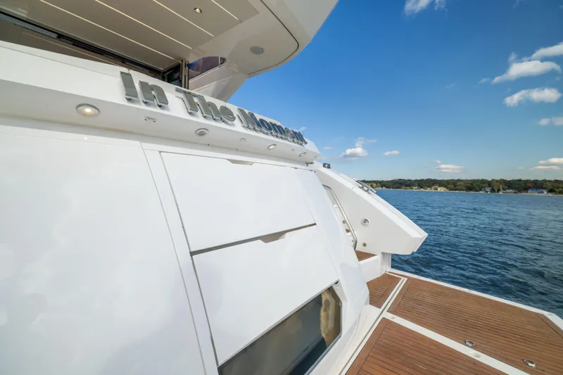 In The Moment Yacht Photos Pics 2018 Sunseeker Manhattan 52 yacht on water, featuring sleek design and wooden deck.