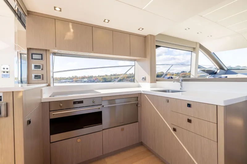 In The Moment Yacht Photos Pics Modern kitchen interior on 2018 Sunseeker Manhattan 52 yacht, featuring sleek cabinetry and appliances.
