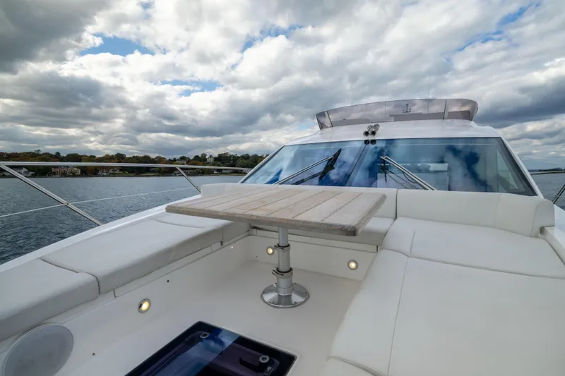 In The Moment Yacht Photos Pics 2018 Sunseeker Manhattan 52 yacht deck with seating and table, under cloudy sky.