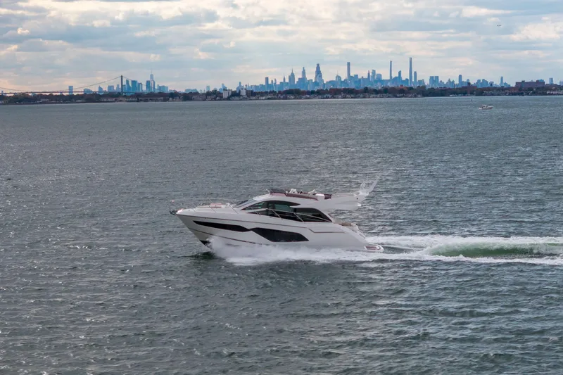 In The Moment Yacht Photos Pics 2018 Sunseeker Manhattan 52 yacht cruising with city skyline in the background.