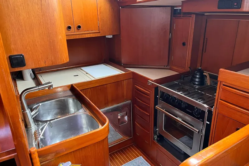  Yacht Photos Pics Interior of 1990 Nautor Swan 61 yacht kitchen with wooden cabinetry and stainless steel appliances.