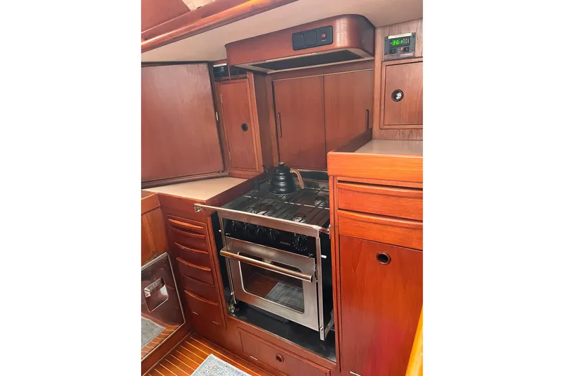  Yacht Photos Pics Galley kitchen in 1990 Nautor Swan 61 yacht with wooden cabinetry and stove.