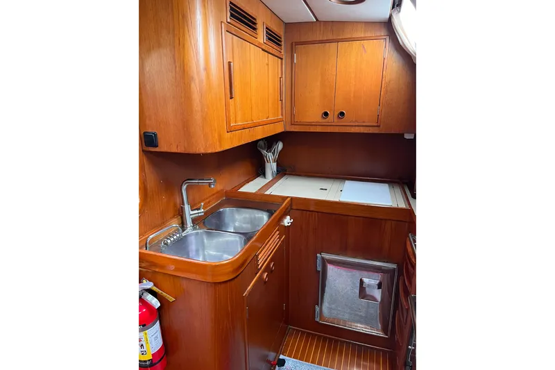  Yacht Photos Pics Wooden galley interior of 1990 Nautor Swan 61 yacht with double sink and storage cabinets.