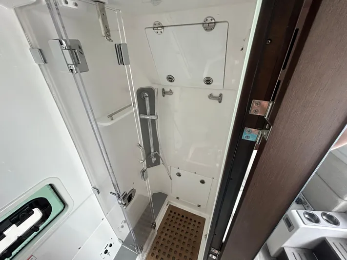  Yacht Photos Pics 2023 Everglades 455 boat interior shower with glass door and wooden floor mat.