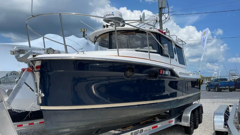  Yacht Photos Pics 2022 Ranger Tugs R-25 boat on trailer, blue hull, docked outdoors under cloudy sky.